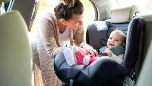 Mother strapping her baby in a car seat.