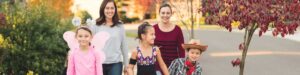 Two mothers walking with their young-trick or treaters.