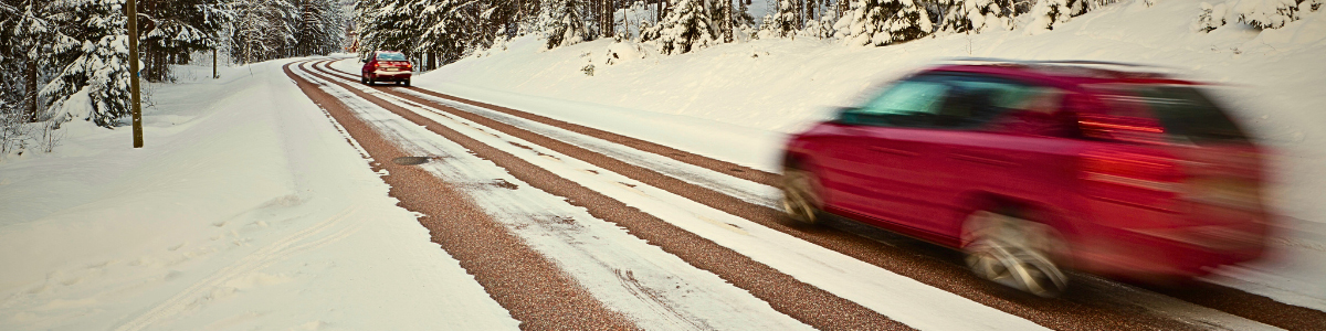Red car with motion blur speeding down a snow covered highway