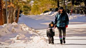 Woman walking her son down a snowy and icy road.