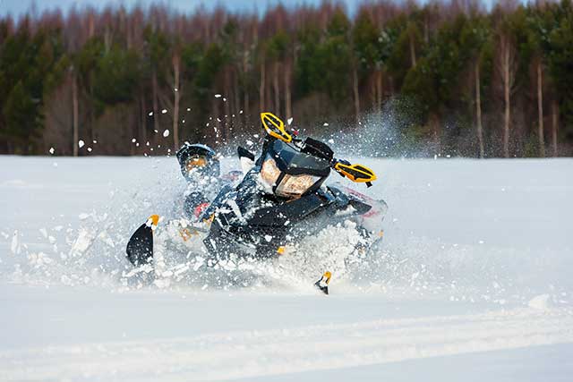 A snowmobile driving fast through the snow