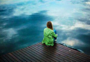 Woman sitting looking at lake alone