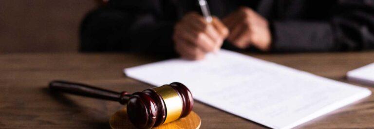 Judge signing papers with gavel in foreground