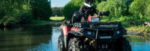 ATV driver wearing a helmet as they drive beside a beautiful lake