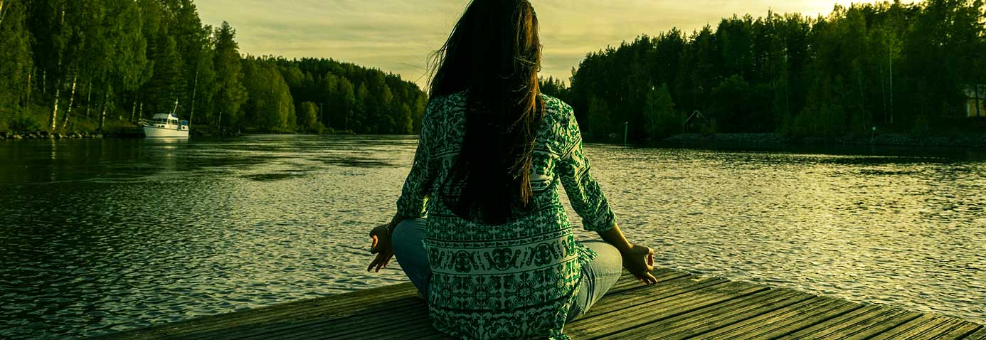 Woman peacefully looking at a lake while doing yoga