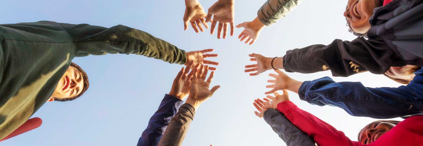 Group of community-minded individuals raising hands together in a circle