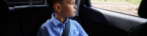 Young boy buckled in his seat with a seat-belt and looking out the window.