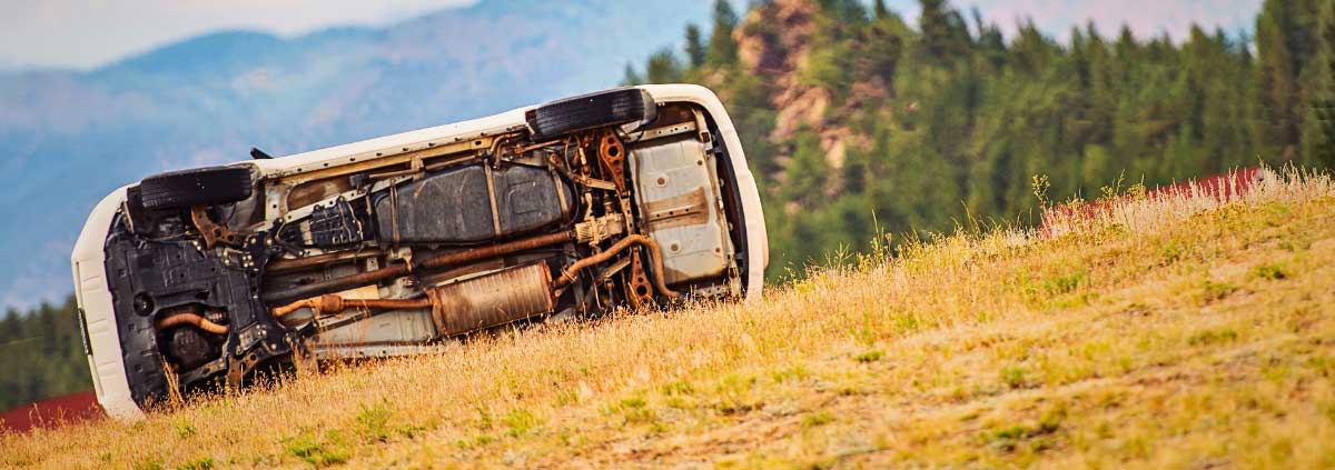 An automobile tipped over on it's side on the side of the road