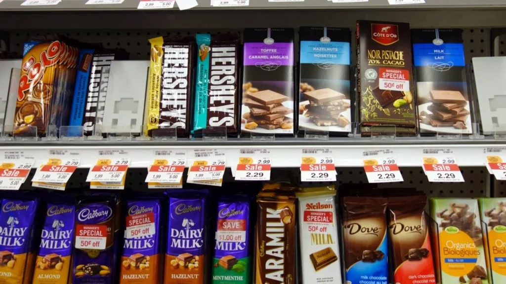 a variety of chocolate brands laid upright on a shelf at a grocery store in canada