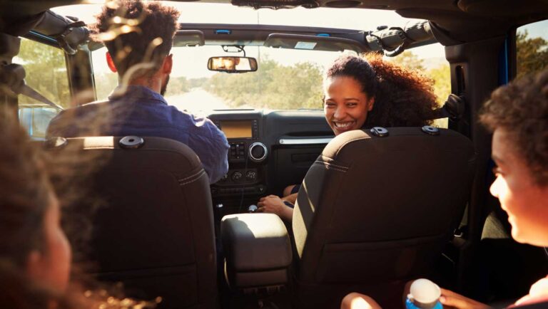 A family in an car driving down the road on a summer road trip