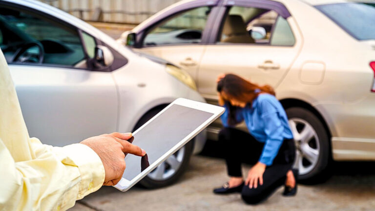 Insurance adjuster working on a tablet at an accident when a woman is kneeling on the ground